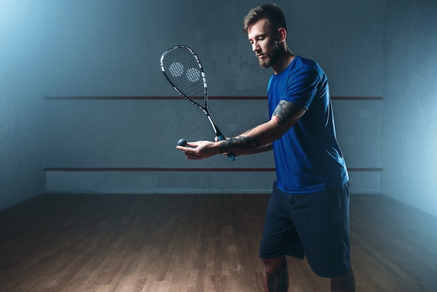 Männlicher Squashspieler mit Schlägertraining auf Innenhof.