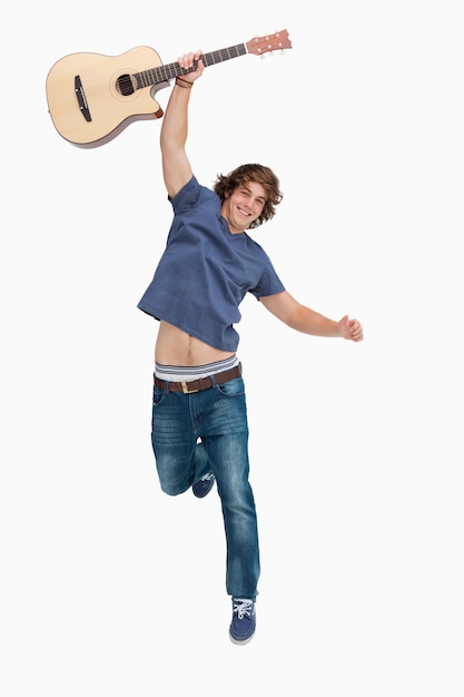 Männlicher Student, der mit seiner Gitarre springt