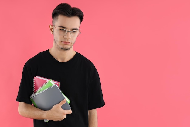 Männlicher Student mit Notizbüchern auf rosa Hintergrund