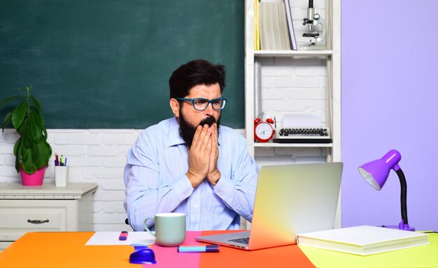 Männlicher Student über grüner Tafel Hintergrund Lehrertag junger ernsthafter Student männlicher Student denkt