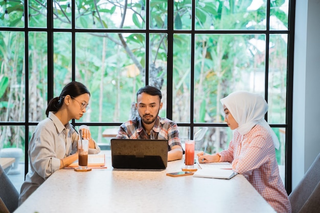 Männlicher Student und zwei Studentinnen, die einen Laptop verwenden