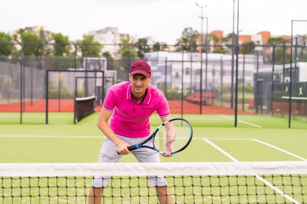 Männlicher Tennisspieler am Gericht, das glücklich schaut