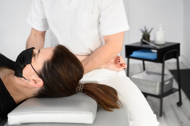 Männlicher Therapeut, der einer Patientin in der Physiotherapieklinik Massage zur Linderung von Schulterschmerzen gibt.
