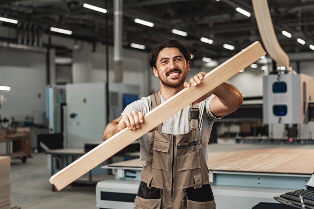 Männlicher Tischler hält Holzbohlen in der Werkstatt