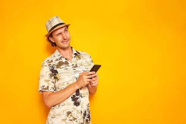 Männlicher Tourist schreibt eine Nachricht auf einem Smartphone, das auf einem gelben Hintergrund mit einem Platz für Text isoliert ist