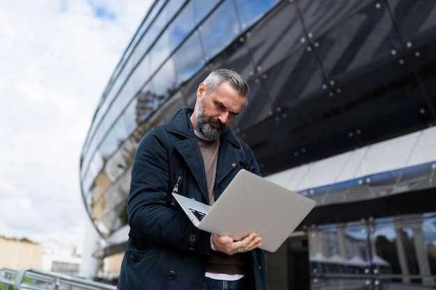 Männlicher Unternehmer, der online an einem Laptop arbeitet, bevor er am Flughafen in ein Flugzeug steigt