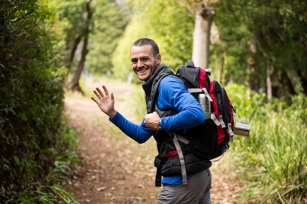 Männlicher Wanderer, der Hand beim Gehen im Wald winkt