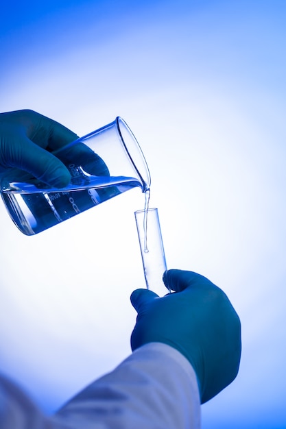 Männlicher Wissenschaftler gießt Flüssigkeit aus Becherglas in Reagenzglas