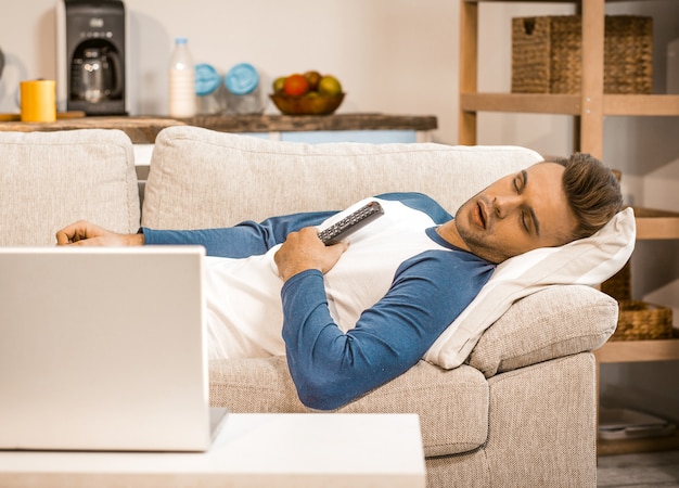 Männliches häusliches Leben und Entspannung auf Sofa zu Hause