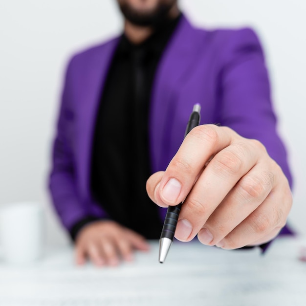 Männliches Model in lila Anzug sitzt am weißen Tisch und zeigt mit Stift auf wichtige Nachricht Gentleman mit kritischer Ankündigung Kaffeetasse an Deck