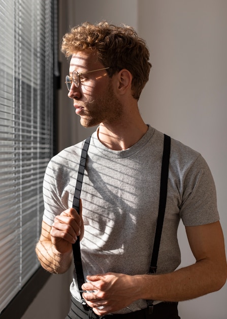 Männliches Modell mit lockigem Haar, das aus der Fenstervorderansicht schaut