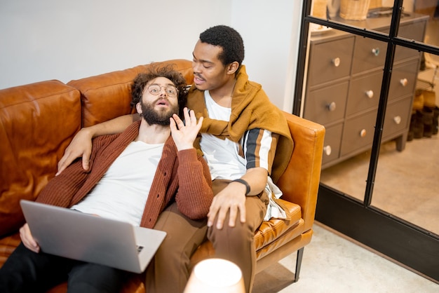 Männliches schwules Paar, das sich zu Hause auf einer Couch unterhält