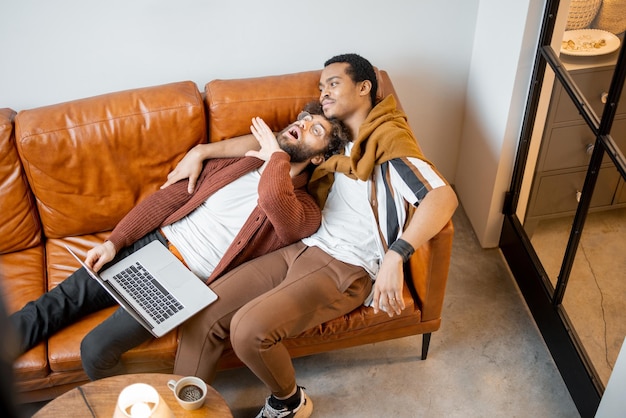 Männliches schwules Paar, das sich zu Hause auf einer Couch unterhält