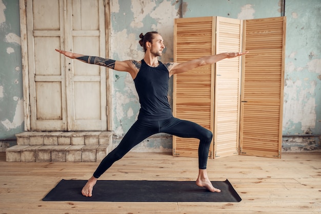 Männliches Yoga, das Dehnungsübung auf Matte tut