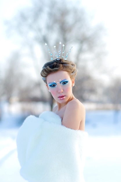 Märchenhaftes Cosplay auf Schneekönigin Frau im Kleid posiert im verschneiten Wald