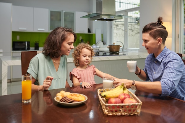 Mães dando a filha copo de leite