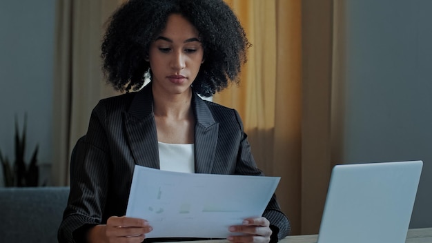 Maestra africana trabajadora mujer de negocios trabaja con documentos gráficos en el control de la oficina en casa