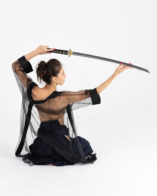 Foto maestra de aikido mujer en el tradicional kimono samurai hakama con cinturón negro con espada katana sobre fondo blanco concepto de estilo de vida saludable y deportes