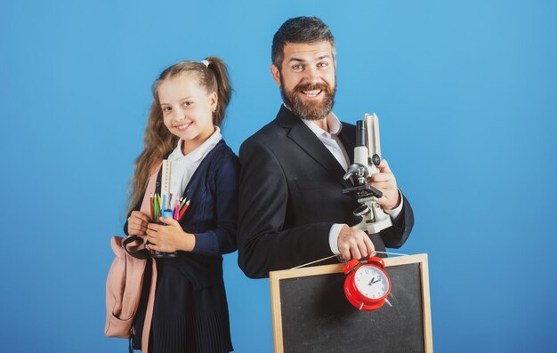 Maestra y alumna colegiala lista para la escuela retrato de papá y niñas con útiles escolares i