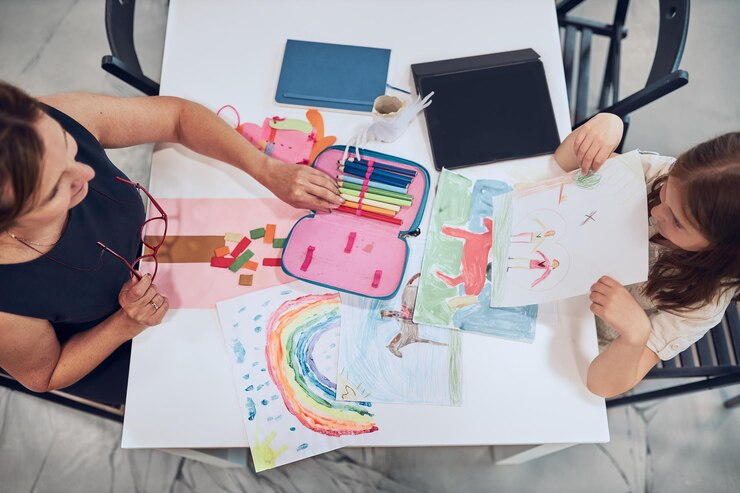 Foto maestra ayudando a una estudiante durante la clase de arte niño haciendo la tarea escuela primaria aprender y divertirse