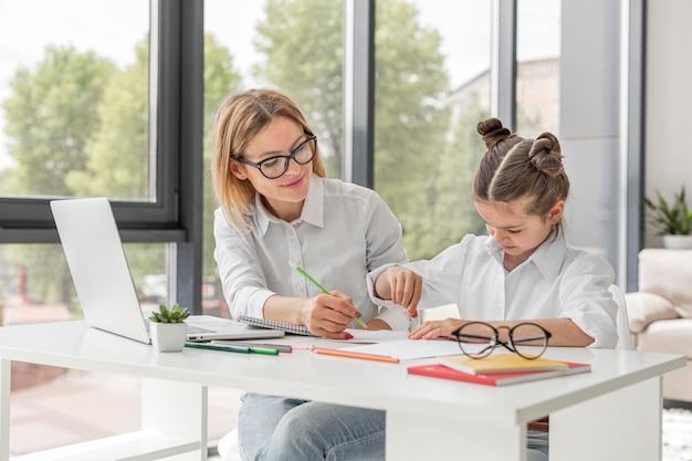 Foto maestra ayudando a su hija a estudiar