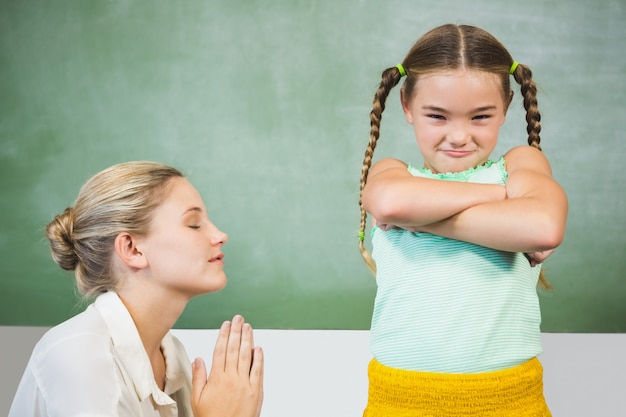 Maestra disculpándose niña en el aula