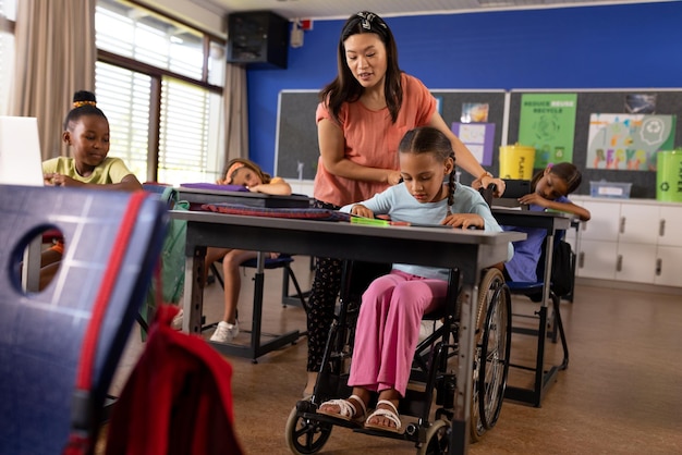 Foto maestra diversa y escolar en silla de ruedas en clase de escuela primaria