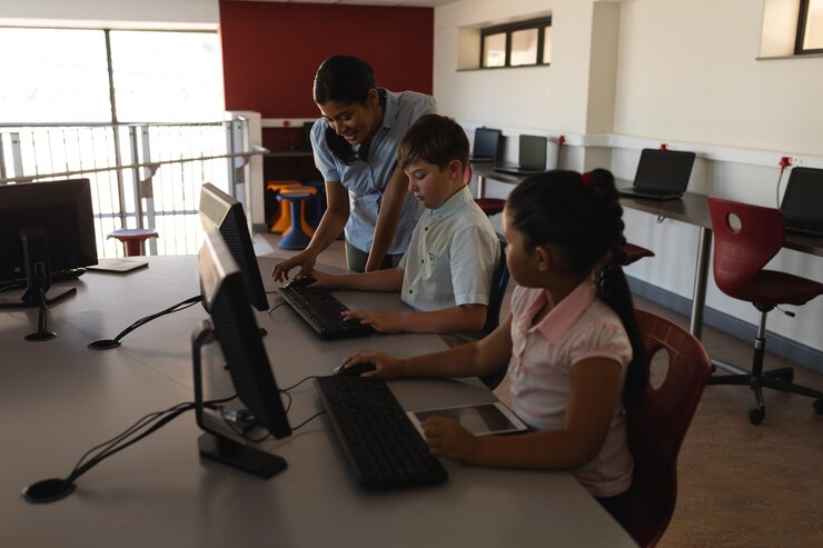 Foto maestra enseñando computadora a un escolar en el escritorio de la escuela