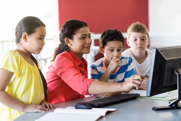 maestra enseñando computadora a niños