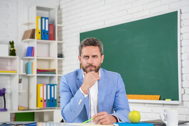 Maestra de escuela seria en el aula en la pizarra