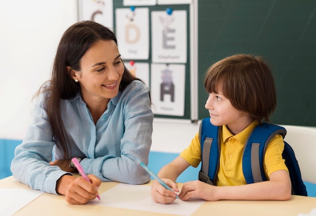 Foto maestra hablando con su alumno en clase