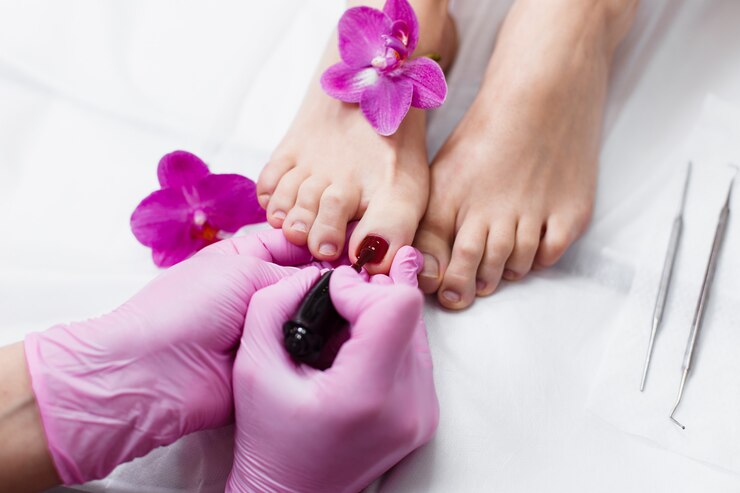 Maestra haciendo pedicura a un cliente en un salón de belleza