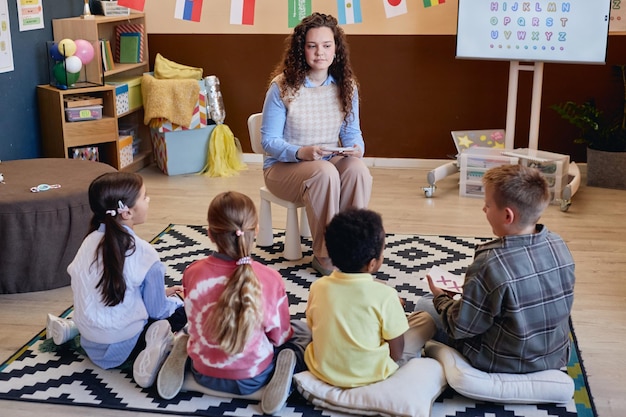 Maestra haciendo tiempo de cuentos en la escuela con un grupo de niños escuchando atentamente