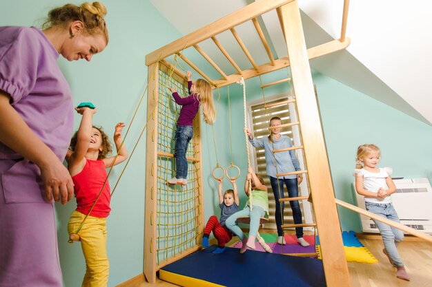 Maestra invita a los niños a hacer ejercicio en un complejo deportivo de madera