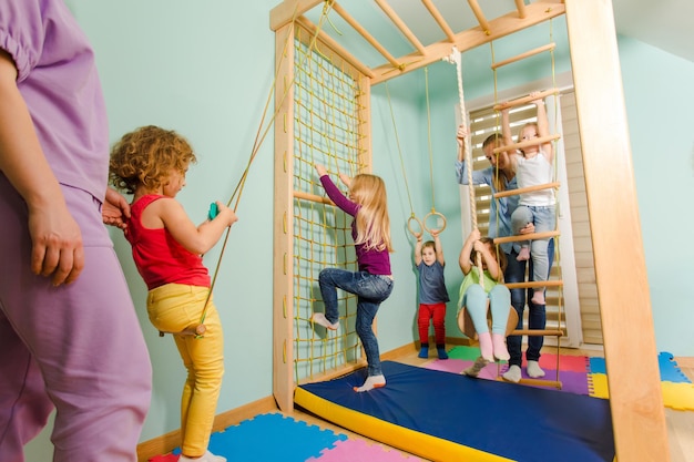 Maestra invita a los niños a hacer ejercicio en un complejo deportivo de madera