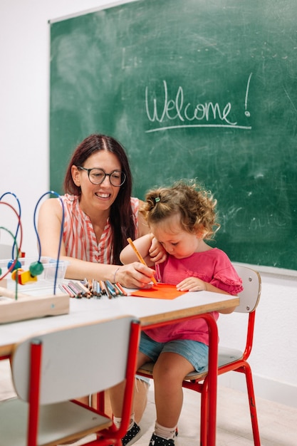 Foto maestra de jardín de infantes apoya al niño en clase