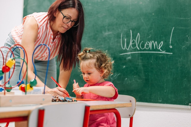 Foto maestra de jardín de infantes apoya al niño en clase