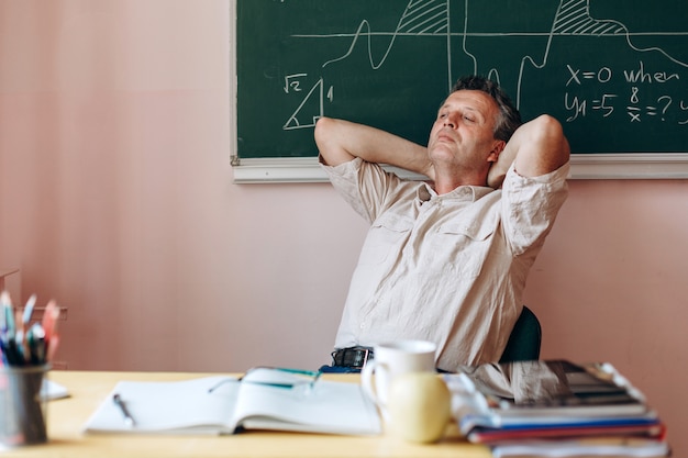 La maestra de mediana edad descansa en el aula y duerme.