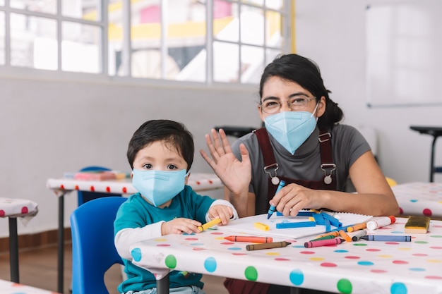 Maestra mexicana y niño con máscaras en la escuela después de la cuarentena del covid-19