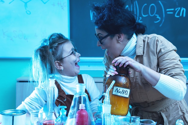 Maestra y niña durante la lección de química mezclando productos químicos