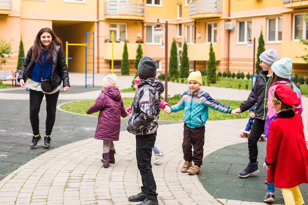 Maestra con niños en preescolar jugar al aire libre juego