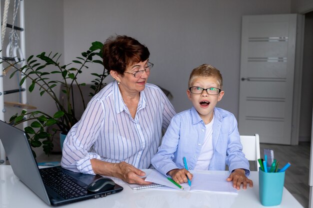 Una maestra o abuela dando clases a un niño en casa.