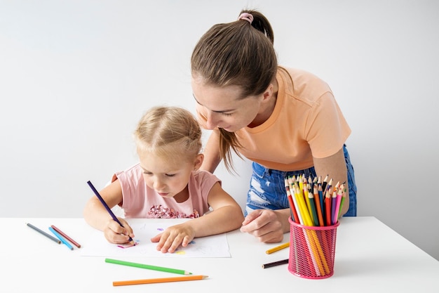 La maestra parece una niña dibuja con lápices de colores sobre papel.