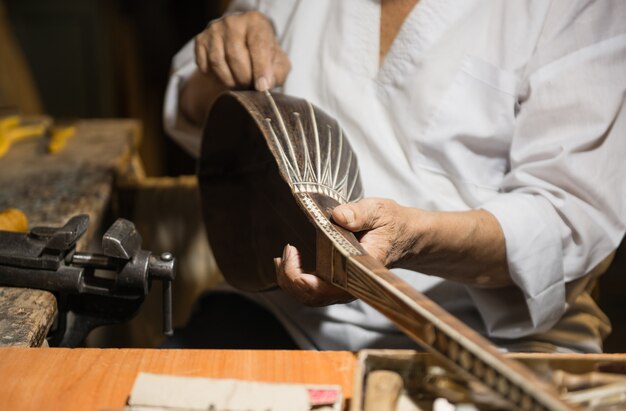 Foto maestro adulto restaura instrumentos musicales antiguos. producción de instrumentos de cuerda