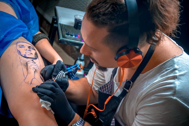 Maestro del arte del tatuaje hace un tatuaje en el cliente en el estudio de tatuajes
