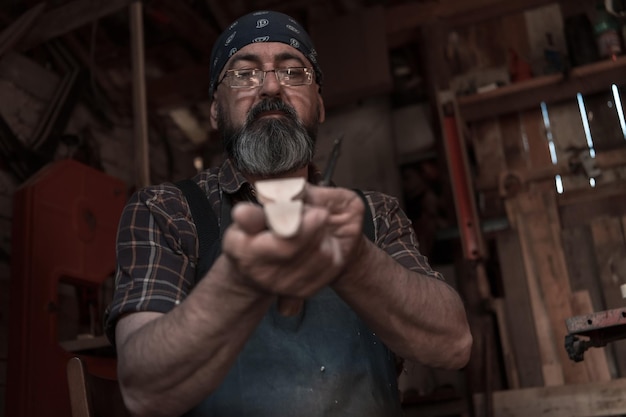 Maestro de artesanía de cucharas en su taller con productos de madera hechos a mano y herramientas que trabajan comprobando la curva y la línea recta. foto de alta calidad