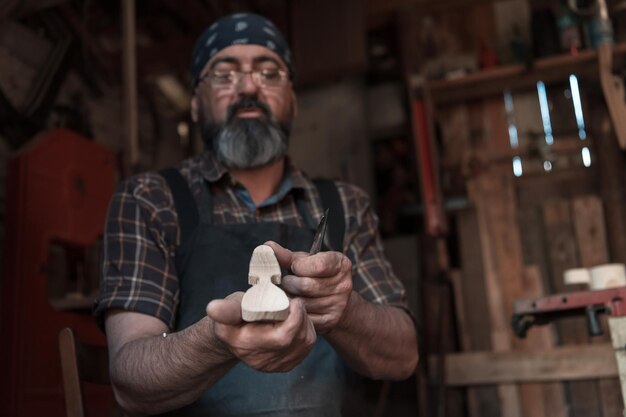 Maestro de artesanía de cucharas en su taller con productos de madera hechos a mano y herramientas que trabajan comprobando la curva y la línea recta. foto de alta calidad