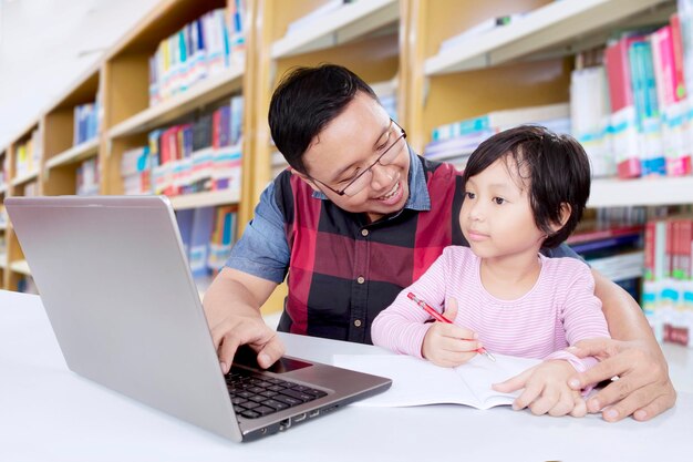 El maestro asiático enseña a la estudiante en la biblioteca.
