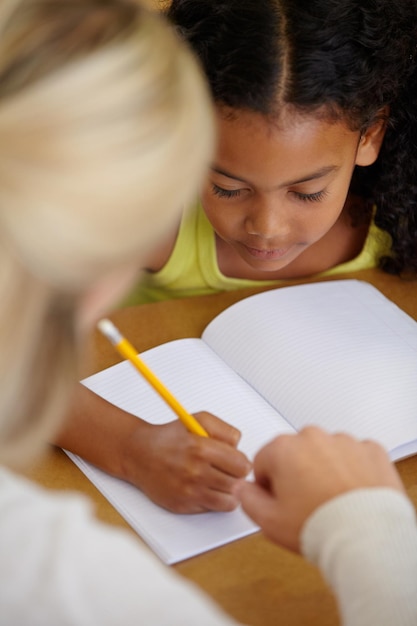 El maestro ayuda a los estudiantes a educar y escribir en un cuaderno con lápiz, enseñanza y aprendizaje para el crecimiento y el desarrollo. Personas en el aula para aprender estudios académicos con niñas y mujeres en la escuela.