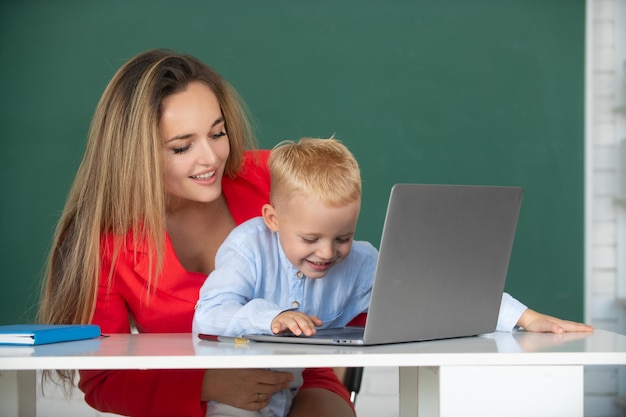 El maestro ayuda a los niños de la escuela a aprender lecciones usando una computadora portátil madre e hijo aprendiendo